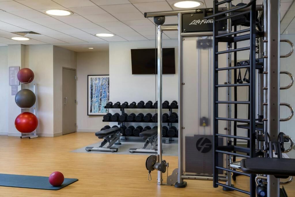 A gym with exercise equipment, dumbbells, and exercise balls.