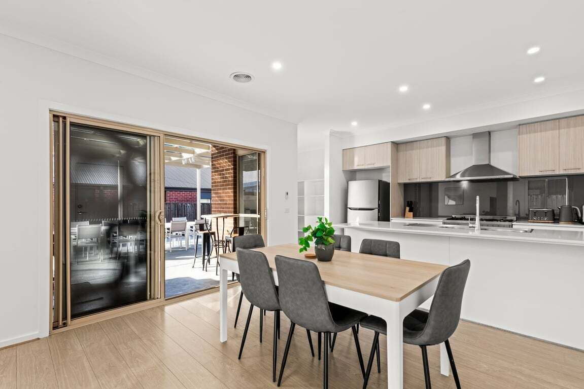 A modern kitchen with white cabinets, a black stove, and a built-in oven.