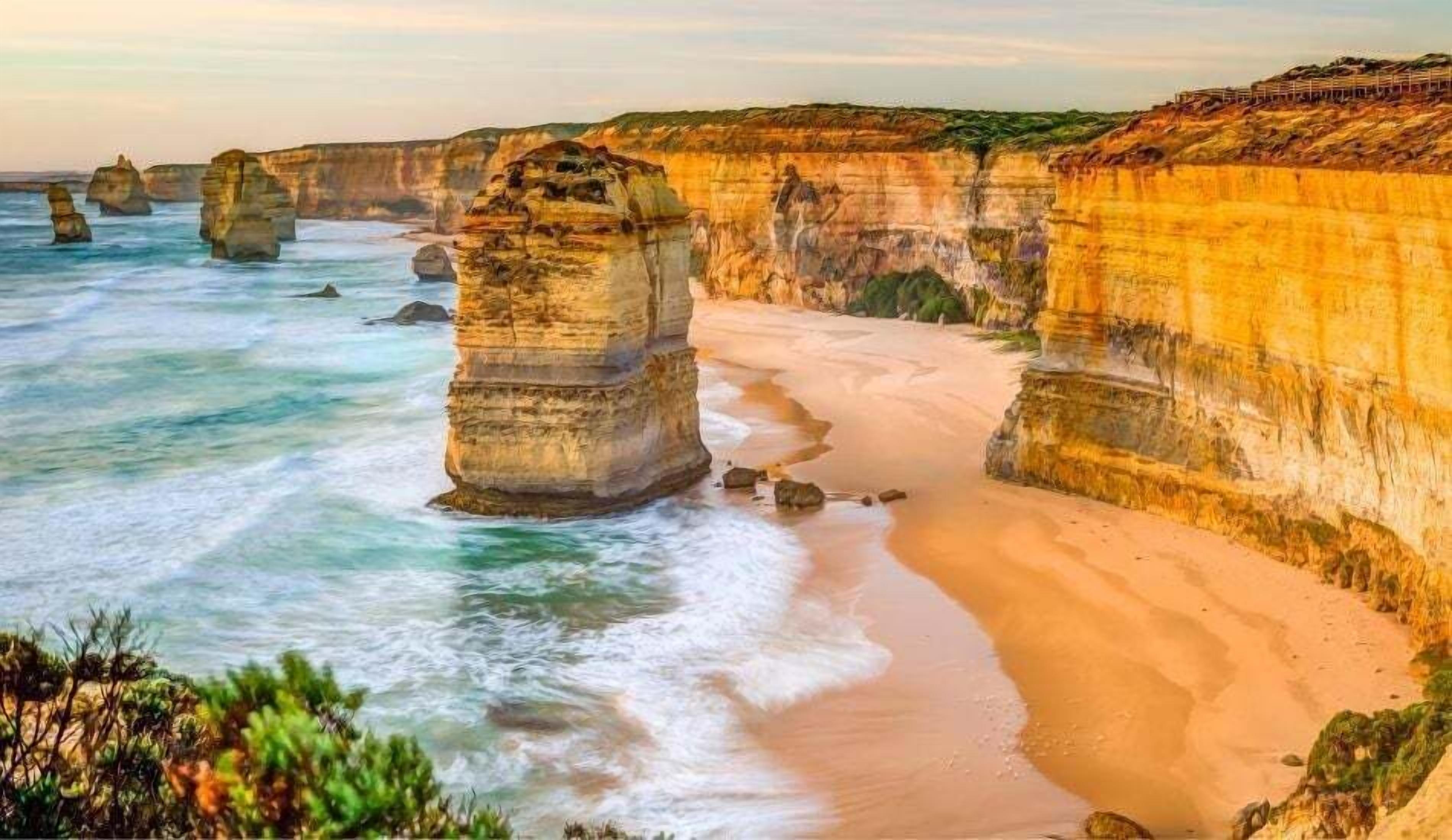 Un paysage côtier caractérisé par d’imposantes formations rocheuses et une plage de sable.