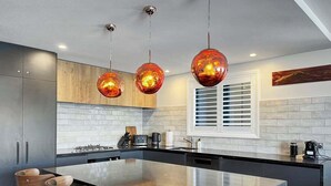 A modern kitchen with a large island, pendant lighting, and wooden bar stools. - Above the Lake | Lakeview Getaway (Queenstown)