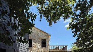 A two-story house with a stone facade, a covered patio, and a garage. - Chef's Kitchen · Game Room+Casita · Group Ready! (Austin)