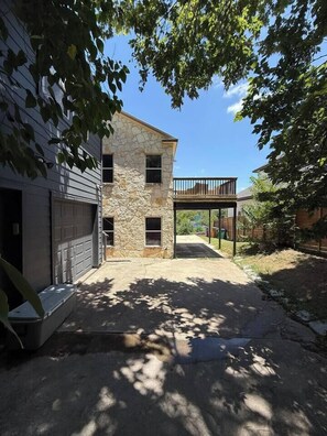 Ein zweistöckiges Haus mit Steinaußenwand, einer überdachten Terrasse und einer Garage.