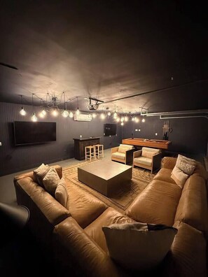 Ein modernes Wohnzimmer mit einer großen Couch, einem Couchtisch und einem an der Wand montierten Flachbildfernseher.