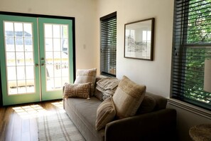A living room with a sofa, pillows, a rug, a framed picture, and a door with glass panels. - Chef's Kitchen · Game Room+Casita · Group Ready! (Austin)