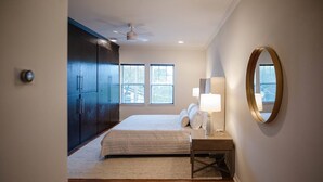 A bedroom with a bed, bedside lamps, a ceiling fan, and a large mirror on the wall. - Chef's Kitchen · Game Room+Casita · Group Ready! (Austin)