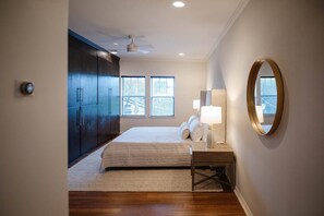 Ein Schlafzimmer mit einem Bett, Nachttischlampen, einem Deckenventilator und einem großen Spiegel an der Wand.