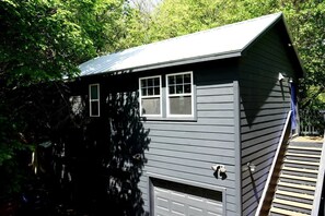 Ein kleines, eingeschossiges Gebäude mit Garage, Eingangstür und einer kleinen Veranda mit Stufen.