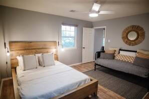A bedroom with a bed, a sofa, a ceiling fan, and a window. - Chef's Kitchen · Game Room+Casita · Group Ready! (Austin)