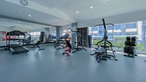 Ett gym med träningsutrustning, en klocka och stora fönster.
