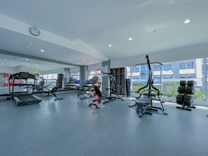 A gym with exercise equipment, a clock, and large windows. - Relaxing, Cozy Apartment on the 20th Floor! AC Wi-Fi Pool (San Jose)