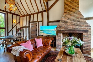 A cozy living room with a fireplace, a leather sofa, and a television. - Peggy Thaxted Barn Collection
Stunning Luxury Country Barn with 4 bedrooms (Thaxted)