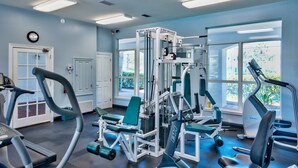 A gym with various exercise equipment, large windows, and a clock on the wall. - The Cayman House: Steps from Beach | Pool & Clubhouse Amenities (Destin)