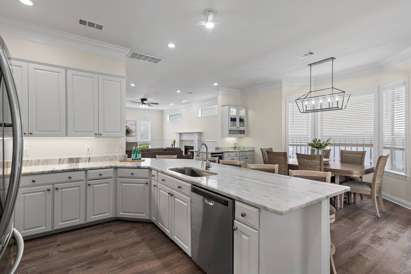 A modern kitchen with white cabinetry, a marble countertop, and a built-in dishwasher.
