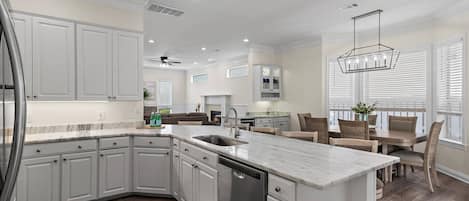 A modern kitchen with white cabinetry, a marble countertop, and a built-in dishwasher.