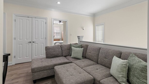 A living room with a sectional sofa, a door, a ceiling fan, and a window. - The Cayman House: Steps from Beach | Pool & Clubhouse Amenities (Destin)
