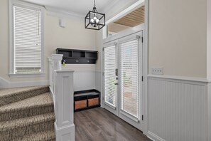 A hallway with a staircase, a black storage unit, and a door with a window. - The Cayman House: Steps from Beach | Pool & Clubhouse Amenities (Destin)