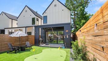 Een modern woonhuis met een verzorgd gazon, terrasmeubilair buiten en een houten omheining.