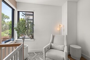 Een moderne kamer met een witte stoel, een klein tafeltje, een potplant en een vloerlamp.