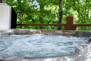 Un jacuzzi con barandilla de madera y vista a zona boscosa.