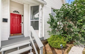 A white house with a red door, a front porch, and a small garden. - Louisville Charm | 3BR | King Beds | Private Yard (Louisville)