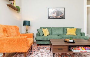 A living room with a sofa, armchair, coffee table, and a framed picture on the wall. - Louisville Charm | 3BR | King Beds | Private Yard (Louisville)