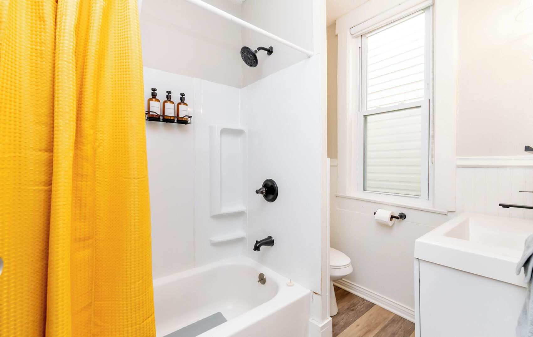 A bathroom with a bathtub, a toilet, and a window.
