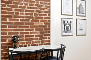 Paredes de tijolos com uma mesa e cadeiras, e quadros pendurados na parede.