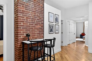 A modern interior with a brick accent wall, a bar area with stools, and framed artwork on the wall.