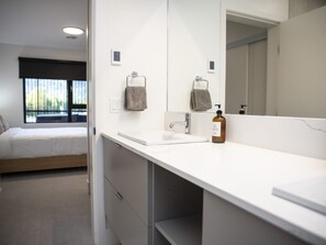 A modern bathroom with a white sink, a mirror, and a bottle of soap. - Revy Mountain Dream (Revelstoke)
