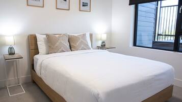A neatly made bed with a wooden headboard, two bedside tables with lamps, and three framed pictures on the wall.