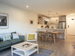 A modern living room with a sofa, coffee table, and dining area with chairs. - Revy Mountain Dream (Revelstoke)