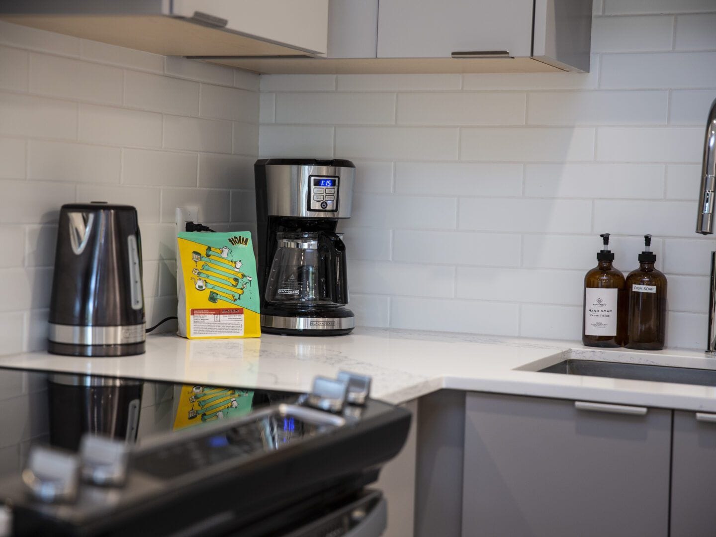 A kitchen with a coffee maker, a box of coffee pods, and two bottles of dish soap.