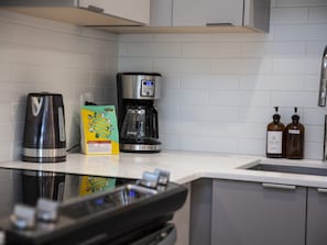 A kitchen with a coffee maker, a box of coffee pods, and two bottles of dish soap. - Revy Mountain Dream (Revelstoke)