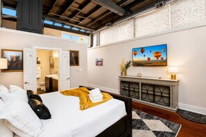Une chambre d’hôtel avec un lit, une cheminée, un tableau représentant des montgolfières et une vue sur le ciel par la fenêtre.