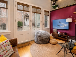 A living room with a large window, a television, a sofa, a bean bag, and a rug. - *New* Wings Over Nulu | Luxury 2BR Industrial Loft (Louisville)