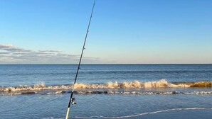 Ett fiskespö på en sandstrand med havet i bakgrunden.