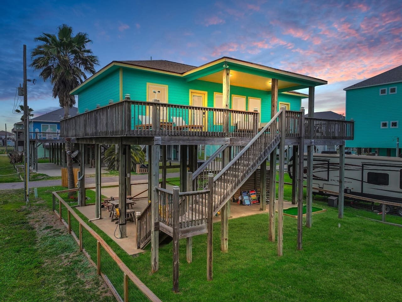 A two-story wooden structure with a balcony, a staircase, and a small deck area.