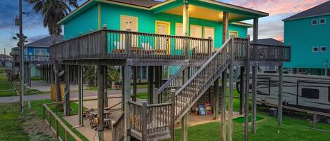 A two-story wooden structure with a balcony, a staircase, and a small deck area.