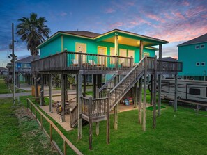 A two-story wooden structure with a balcony, a staircase, and a small deck area.