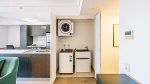 A compact hotel room with a kitchenette, including a washing machine, a small fridge, and a sink. - Modern Two Bedroom Escape in Fortitude Valley (Fortitude Valley)