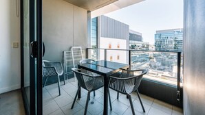 A balcony with a glass table and chairs, offering a city view. - Modern Two Bedroom Escape in Fortitude Valley (Fortitude Valley)