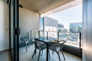 Ein Balkon mit Glastisch und Stühlen und Blick auf die Stadt.