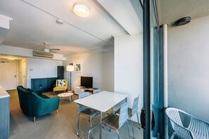Ein modernes Wohnzimmer mit einer Couch, einem Esstisch und einem Fernseher.
