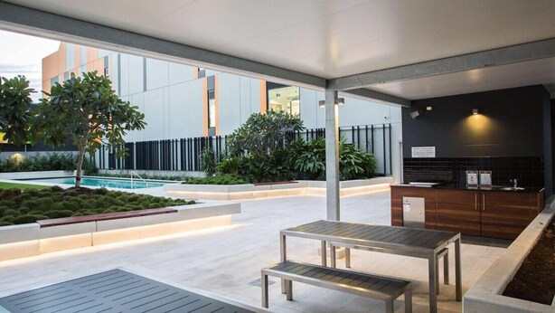 An outdoor patio area with seating, a pool, and a modern kitchen area. - Modern Two Bedroom Escape in Fortitude Valley (Fortitude Valley)