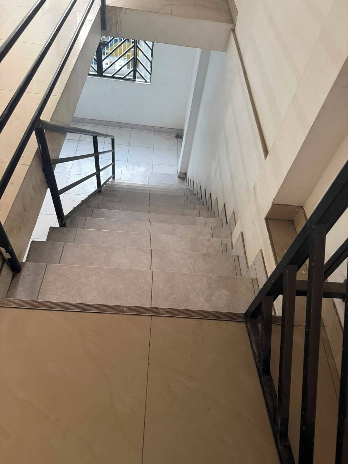 A staircase with a metal railing, leading to a higher floor.