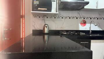 Una cocina con microondas, estufa y hervidor sobre la encimera.