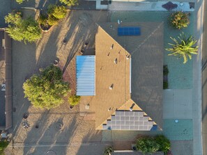 An aerial view of a building with a large solar panel array, a covered outdoor area, and surrounding greenery. - Rolling Hills Haven | 3BR | Large Screened Patio | Fenced Yard | Sun City | Sleeps 6 (Sun City)