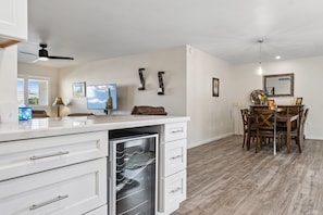 A modern kitchen with white cabinetry, a built-in oven, and a dining area with wooden chairs and a table. - Rolling Hills Haven | 3BR | Large Screened Patio | Fenced Yard | Sun City | Sleeps 6 (Sun City)
