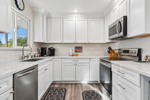 A modern kitchen with white cabinetry, a built-in microwave, and a stainless steel dishwasher. - Rolling Hills Haven | 3BR | Large Screened Patio | Fenced Yard | Sun City | Sleeps 6 (Sun City)