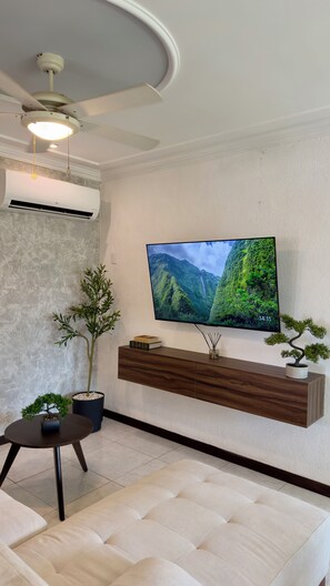 A modern living room with a flat-screen TV, a ceiling fan, and a mounted air conditioner. - Spacious 3-bedroom apartment with a pool in Boca del Río (boca del rio)